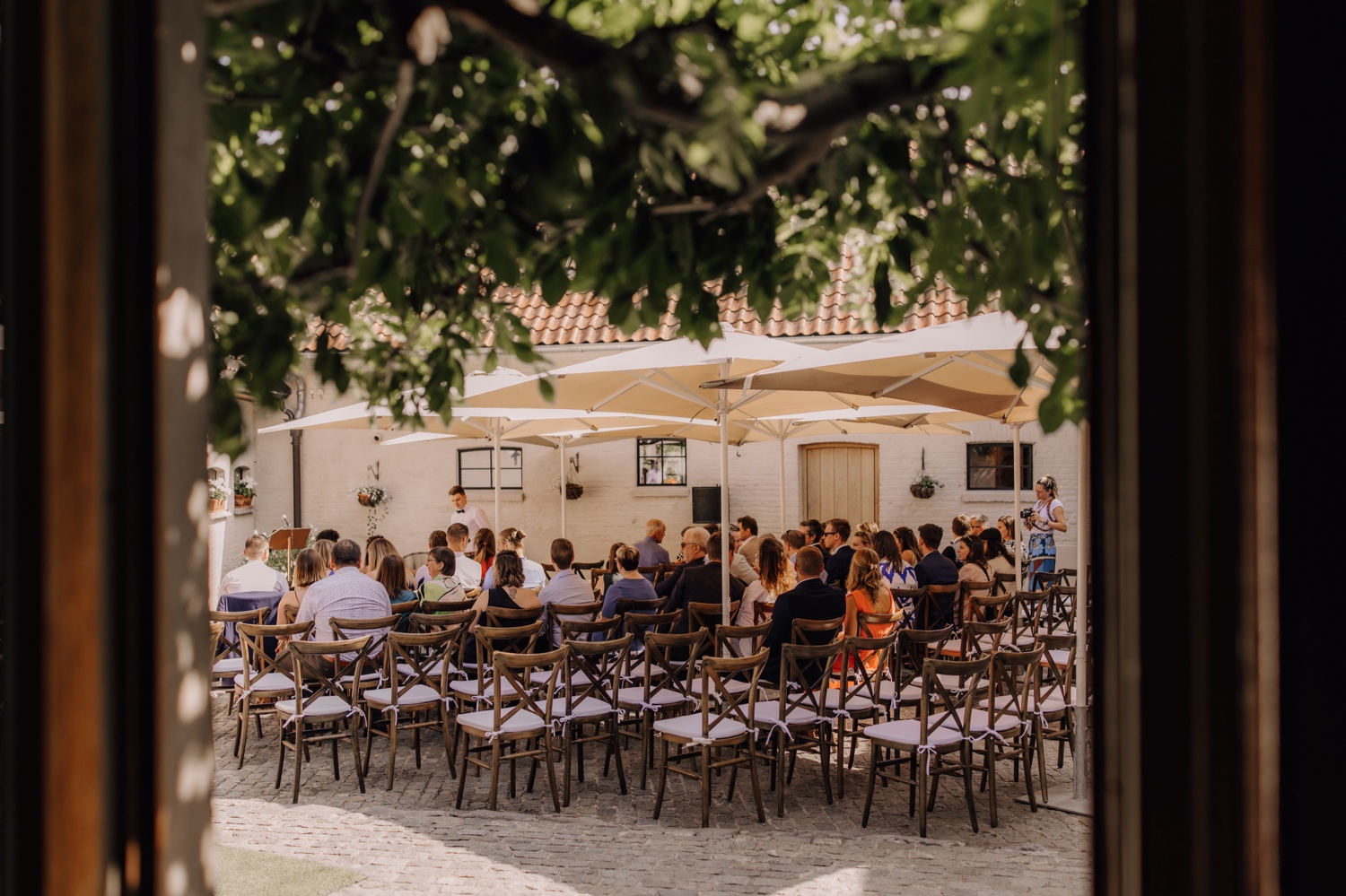 Zomers huwelijk op unieke landelijke locatie in Horebeke - gasten nemen plaats op hun stoel bij de ceremonie opstelling