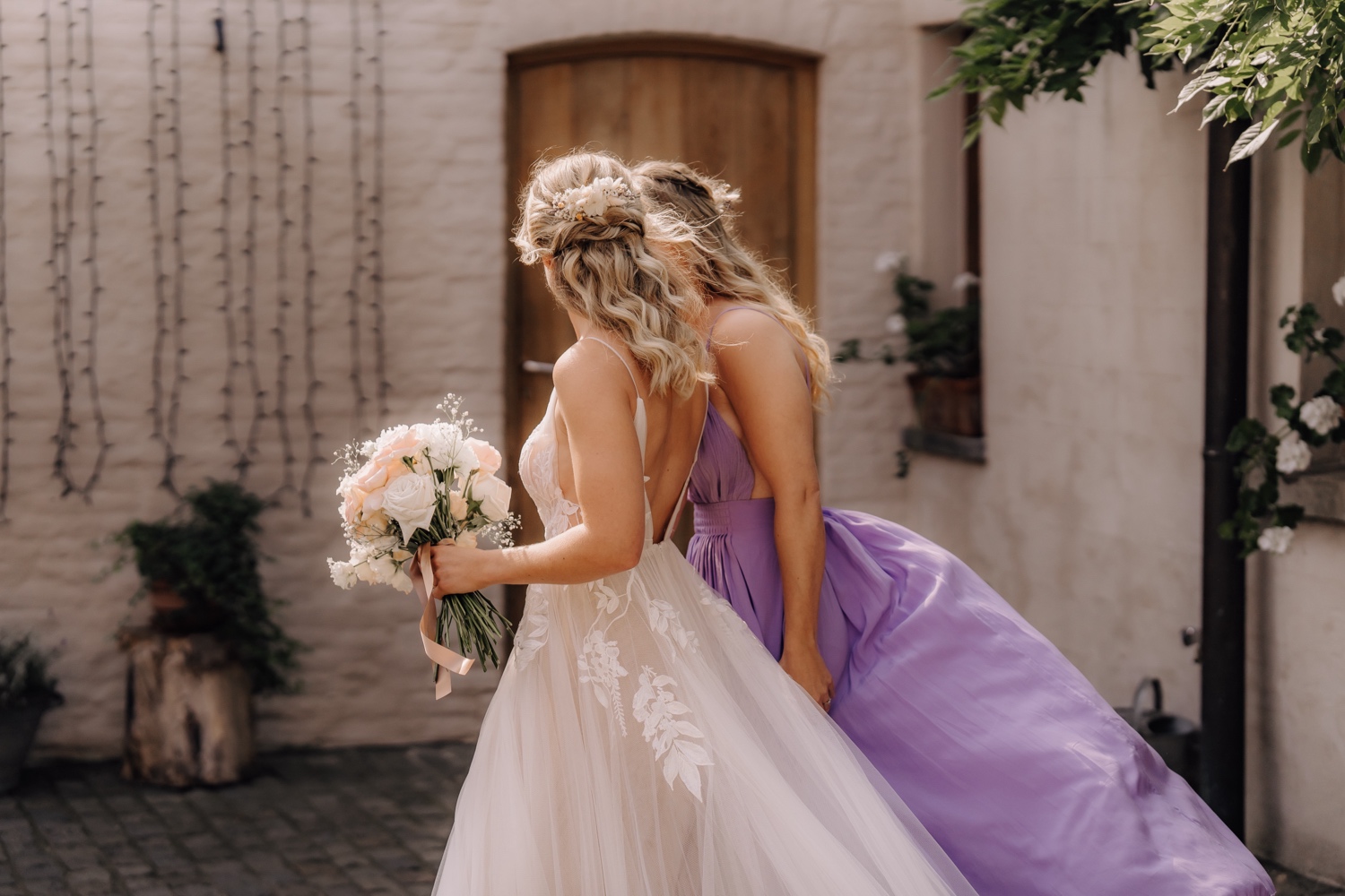 Zomers huwelijk op unieke landelijke locatie in Horebeke - bruid wandelt met haar tweelingzus naar de ceremonie