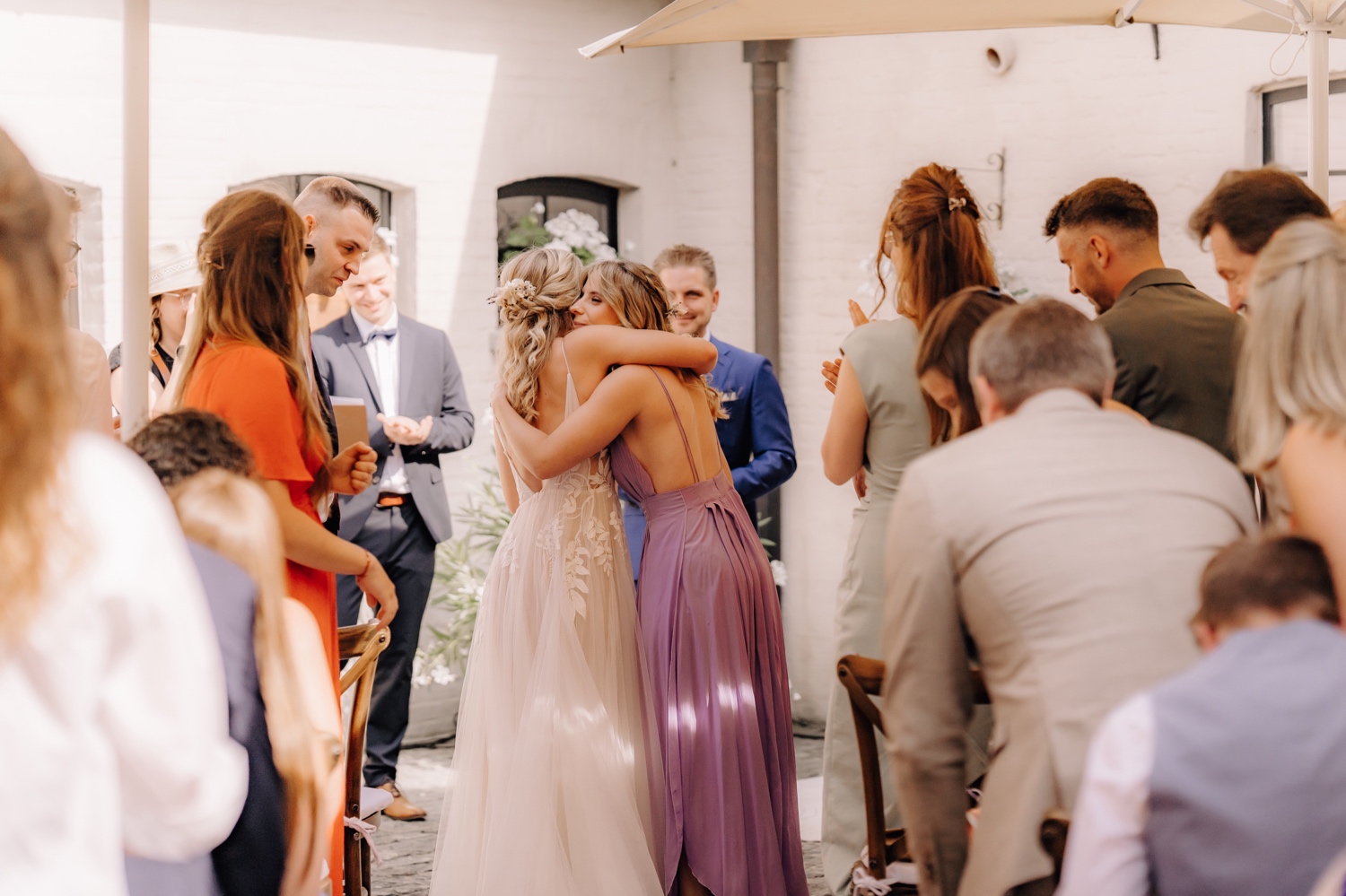 Zomers huwelijk op unieke landelijke locatie in Horebeke - bruid omhelst haar tweelingzus aan het eind van het gangpad