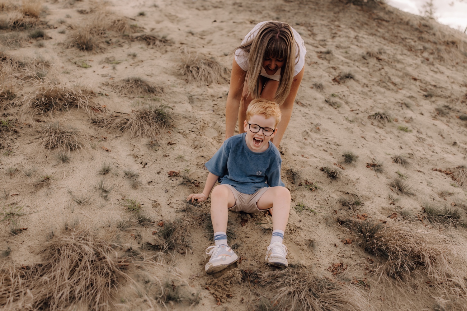 moeder speelt met zoontje in het zand in de Hechtelse duinen