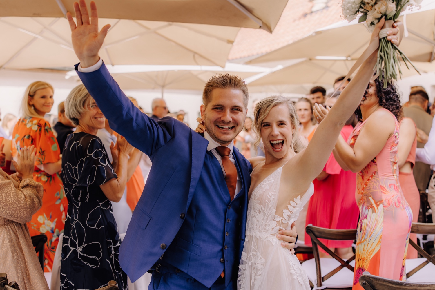 Zomers huwelijk op unieke landelijke locatie in Horebeke - bruidspaar juicht tijdens uittrede van de ceremonie