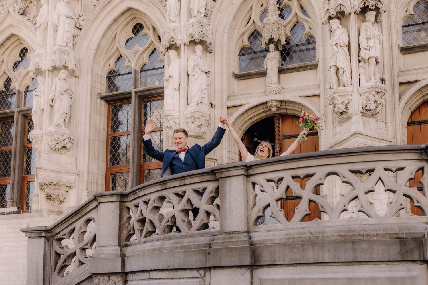 bruidspaar steekt armen in de lucht bij uittrede stadhuis Leuven