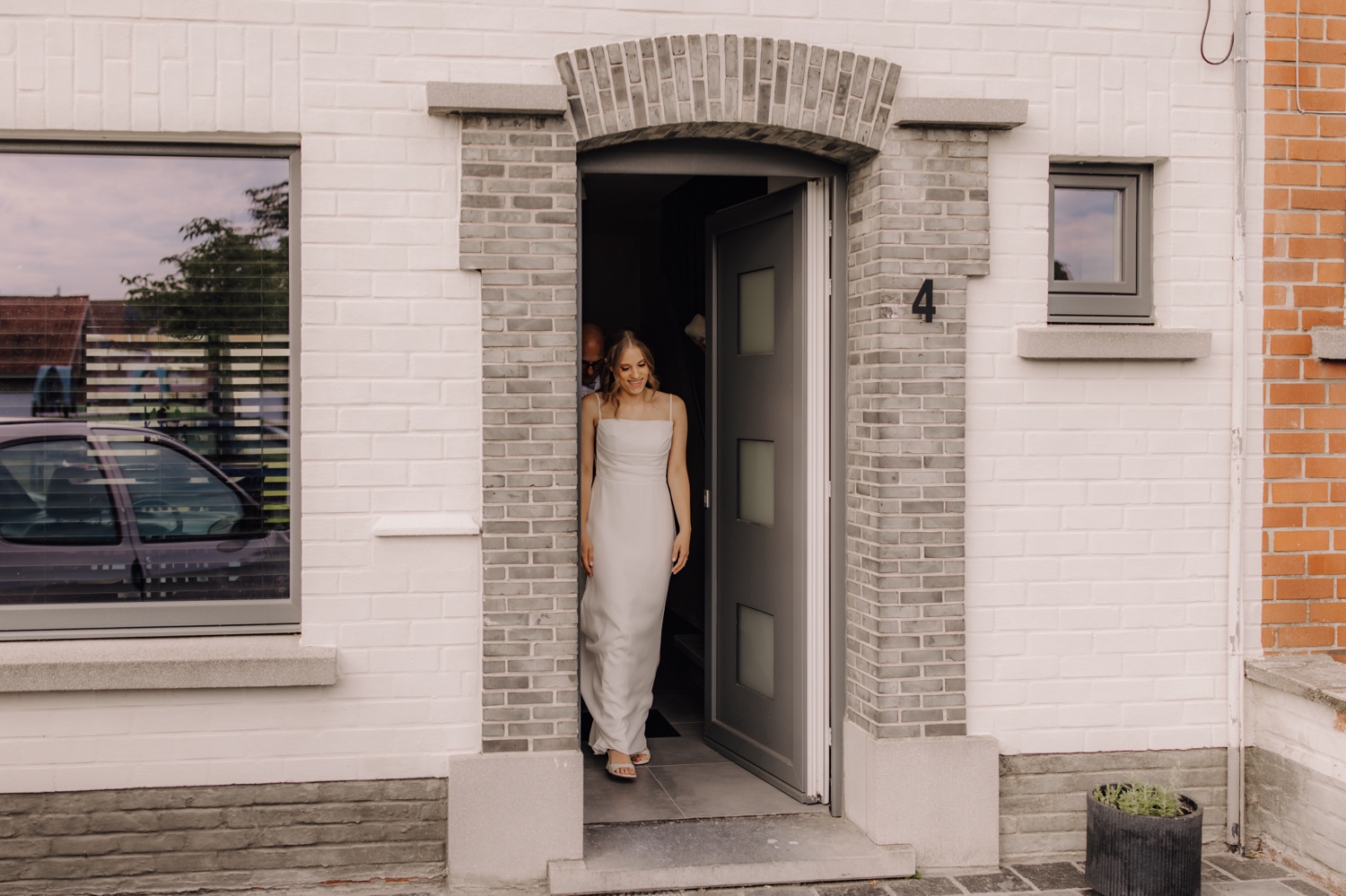 Landelijk huwelijk bij vierkantshoeve Bar Silo - bruid wandelt de deur uit richting bruidegom in Ledegem