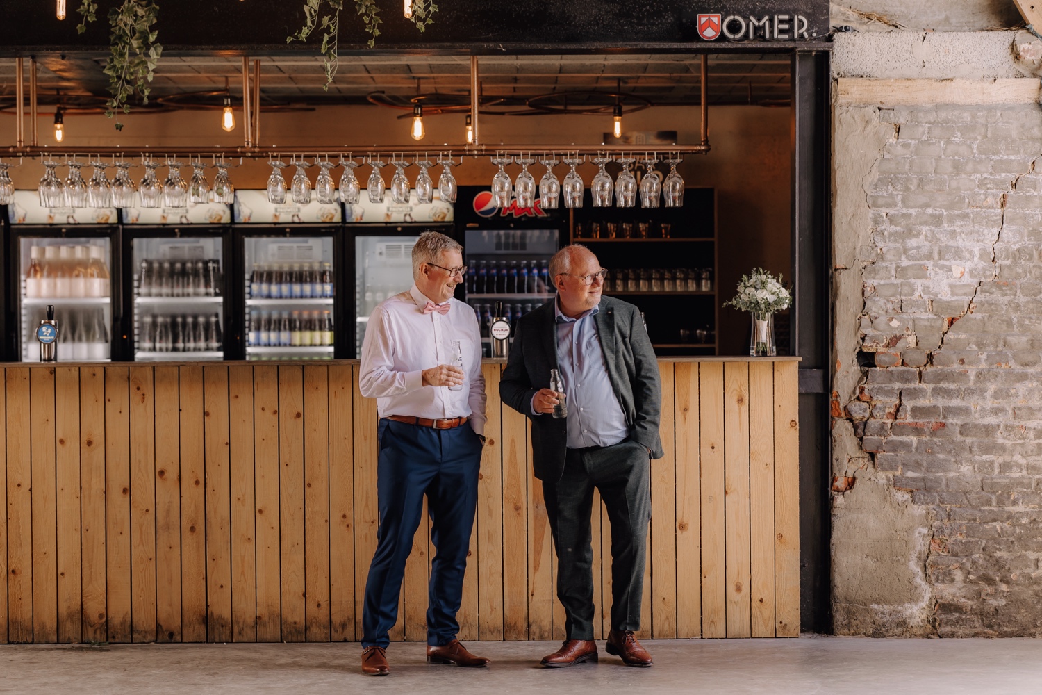 Landelijk huwelijk bij vierkantshoeve Bar Silo - vader van de bruidegom drinkt een watertje aan de bar met de nonkel