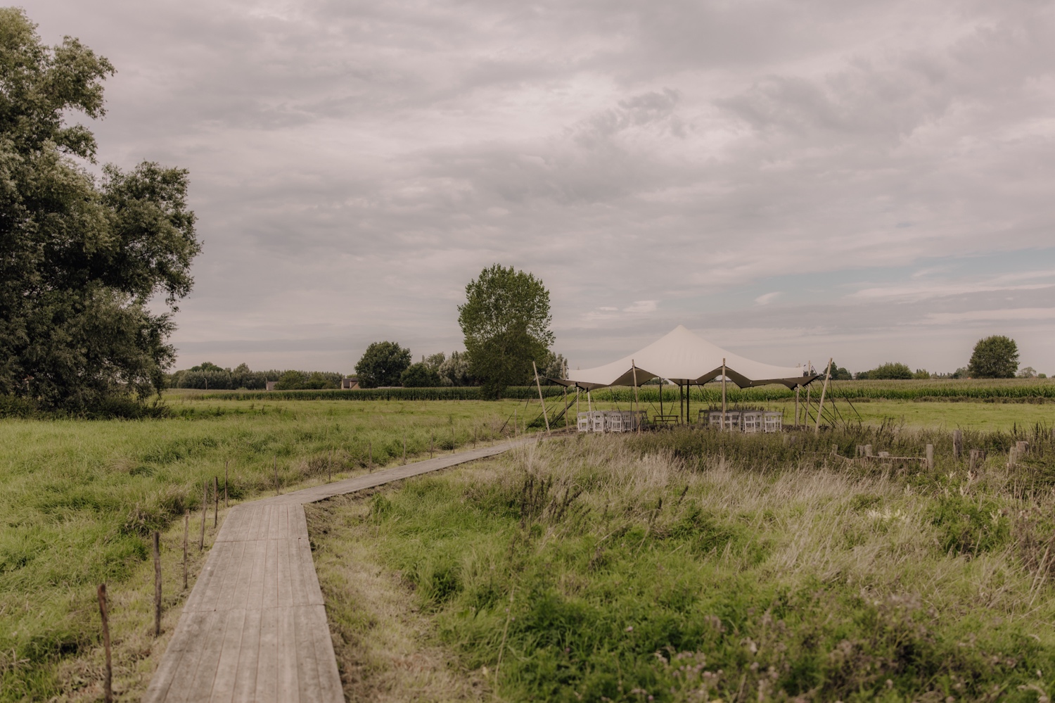 Landelijk huwelijk bij vierkantshoeve Bar Silo - overzichtsfoto van de ceremonietent in de tuin van Bar Silo te Ledegem