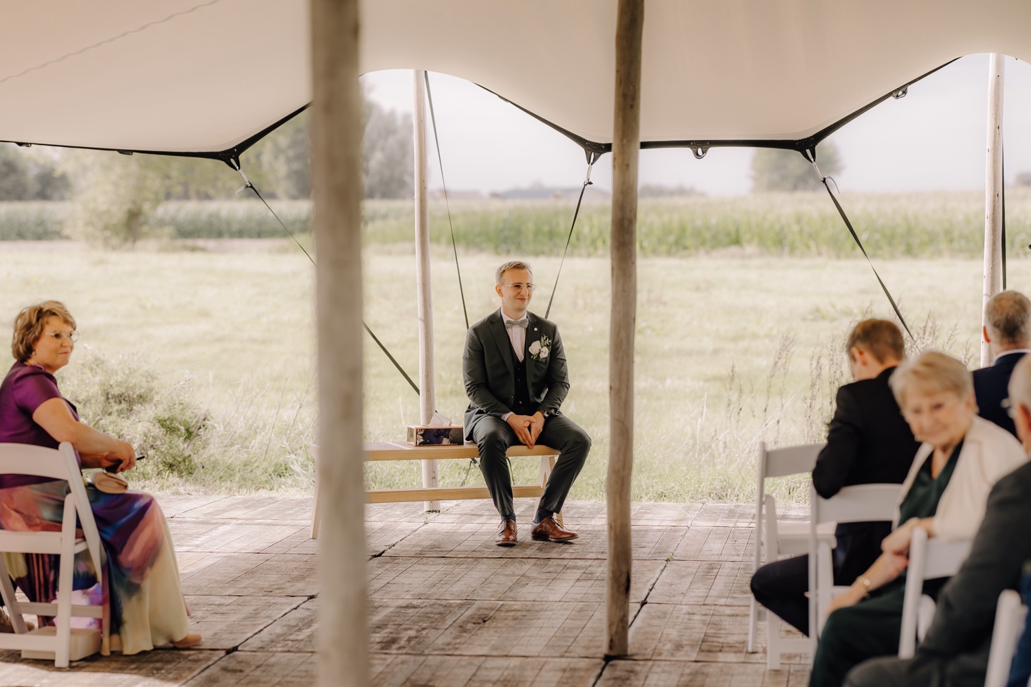 Landelijk huwelijk bij vierkantshoeve Bar Silo - bruidegom wacht op een bankje op zijn bruid tijdens huwelijksceremonie