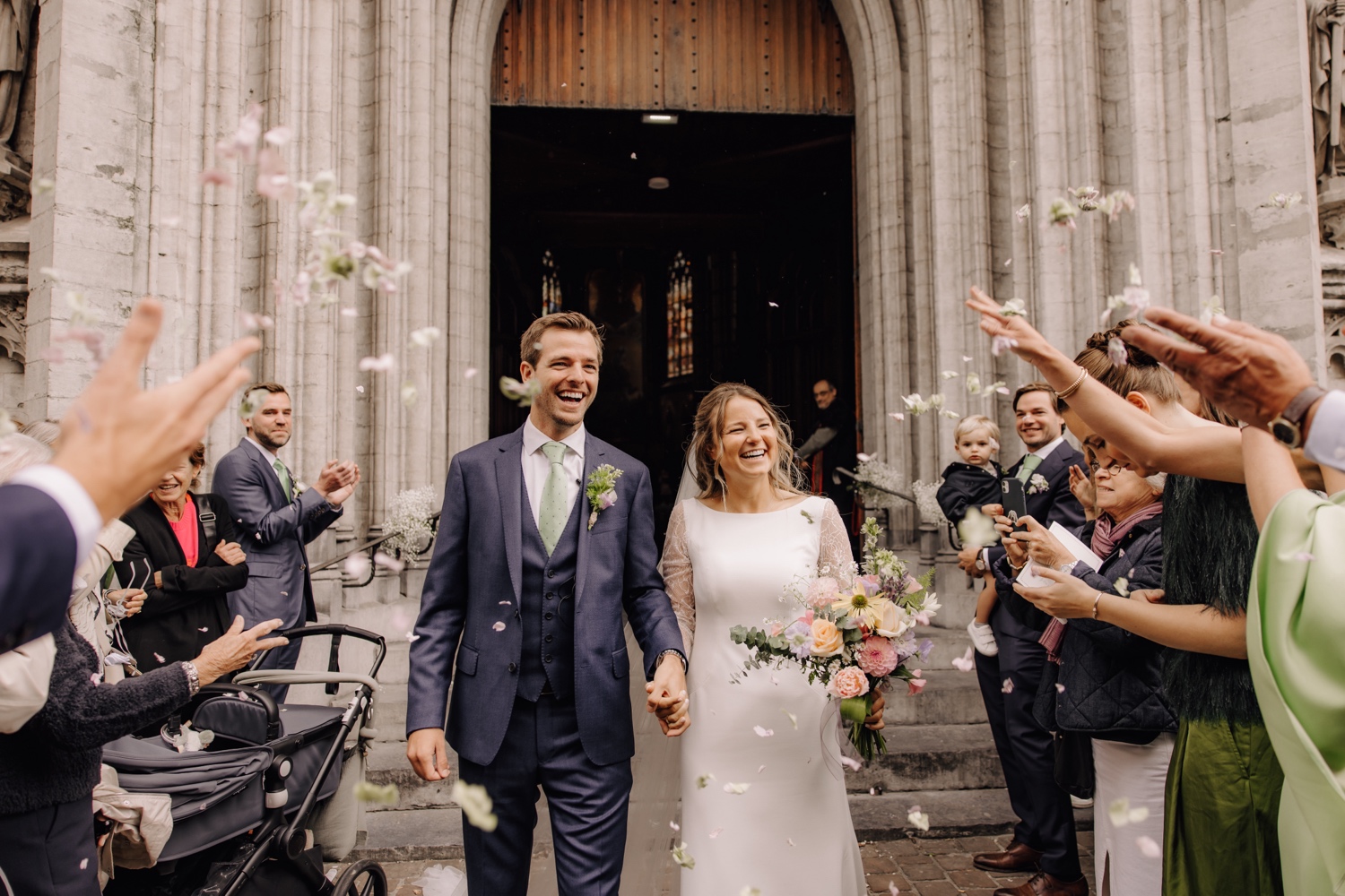 Een regenachtige huwelijksdag bij Hoeve Engelendael - Er worden bloemblaadjes op het bruidspaar gegooid bij buitenkomst kerk