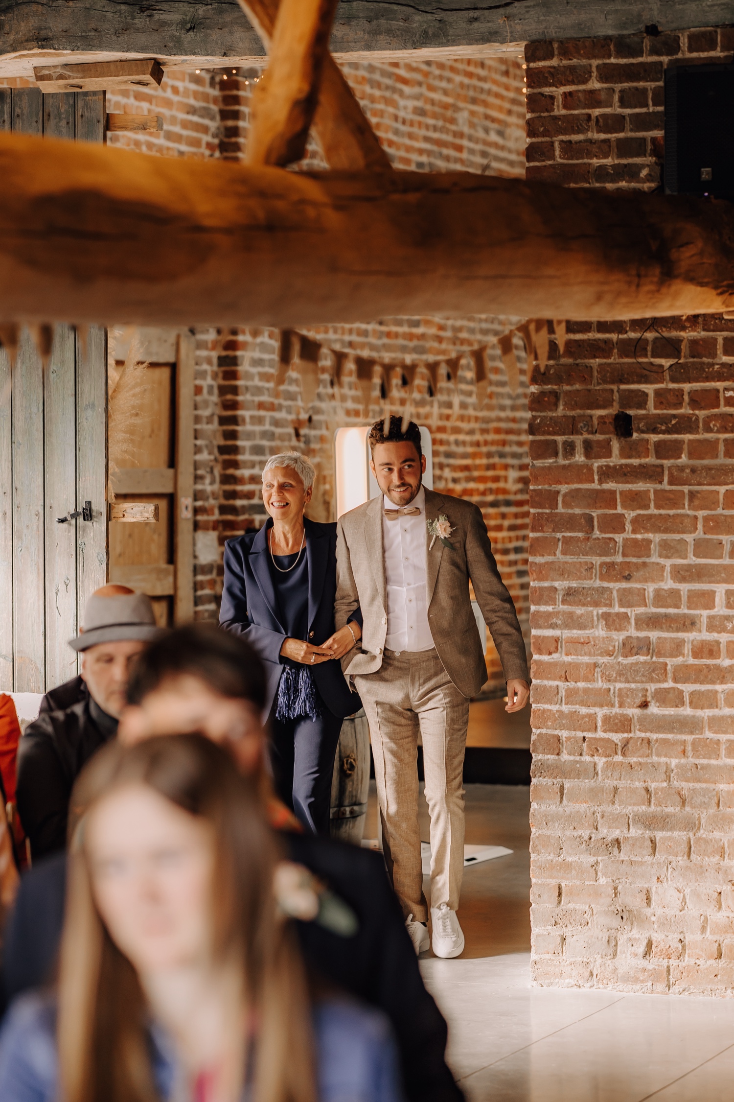 Landelijk huwelijk bij Ferme Koer - bruidegom wandelt met zijn moeder de ceremonie in