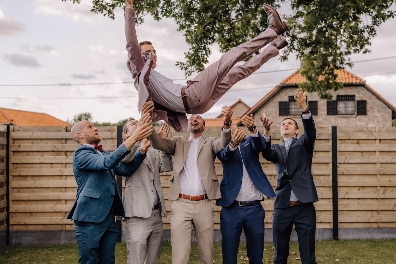 Een intiem huwelijk met twee honden en modderige laarzen - bruidegom wordt in de lucht gegooid door zijn bruidsjonkers