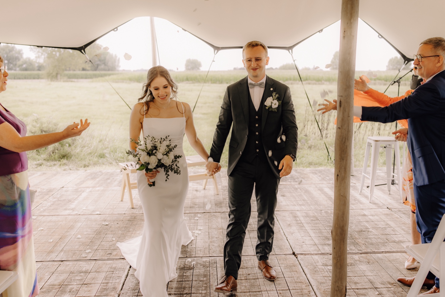 Landelijk huwelijk bij vierkantshoeve Bar Silo - bruidspaar wandelt het gangpad van de ceremonie uit