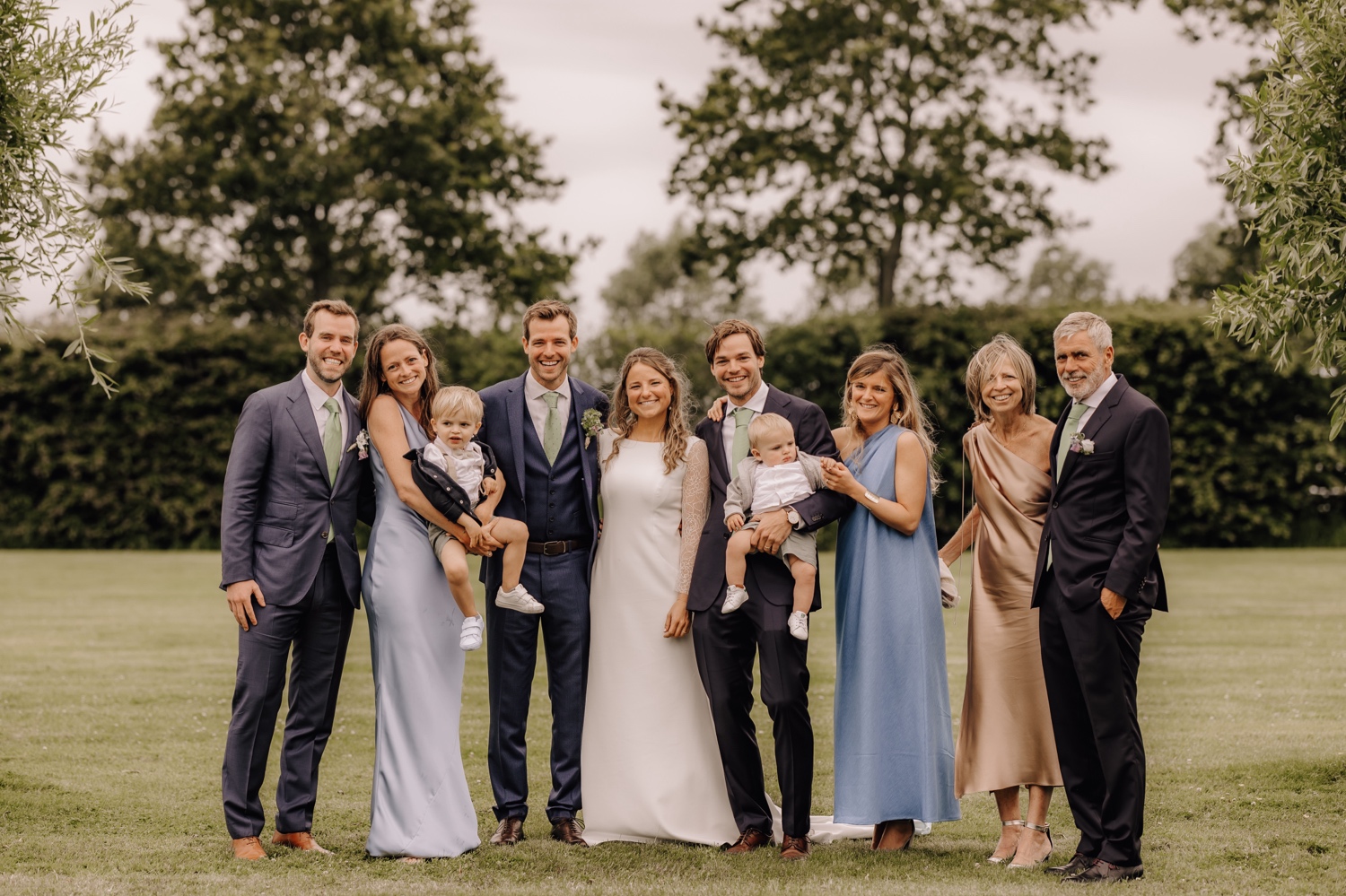 Een regenachtige huwelijksdag bij Hoeve Engelendael - bruidspaar poseert met familie in de tuin