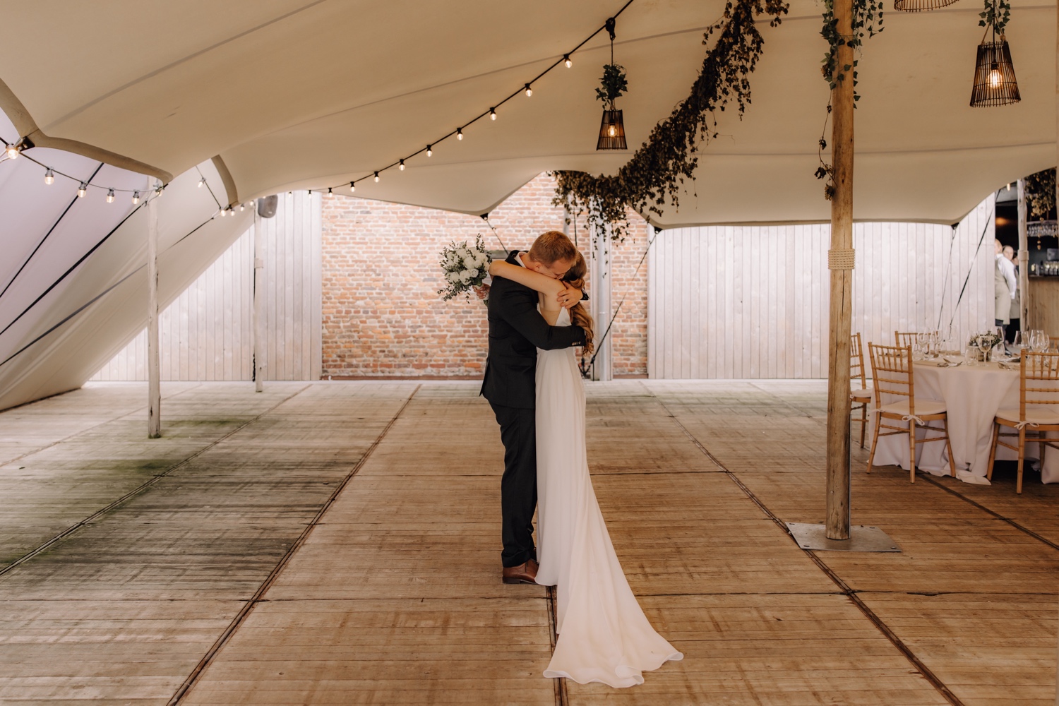 Landelijk huwelijk bij vierkantshoeve Bar Silo - Bruidspaar knuffelt elkaar in de tent van Bar Silo